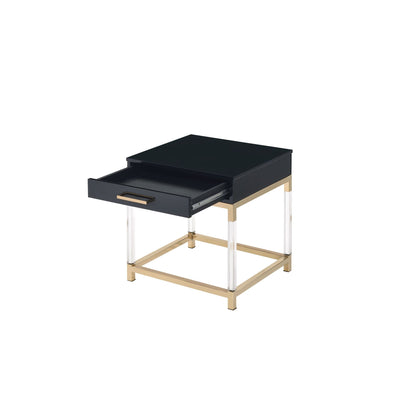 Black high gloss end table with open drawer. The table top rests on a gold frame and has clear acrylic legs that connect to the bottom gold frame. The drawer has a horizontal gold handle. 