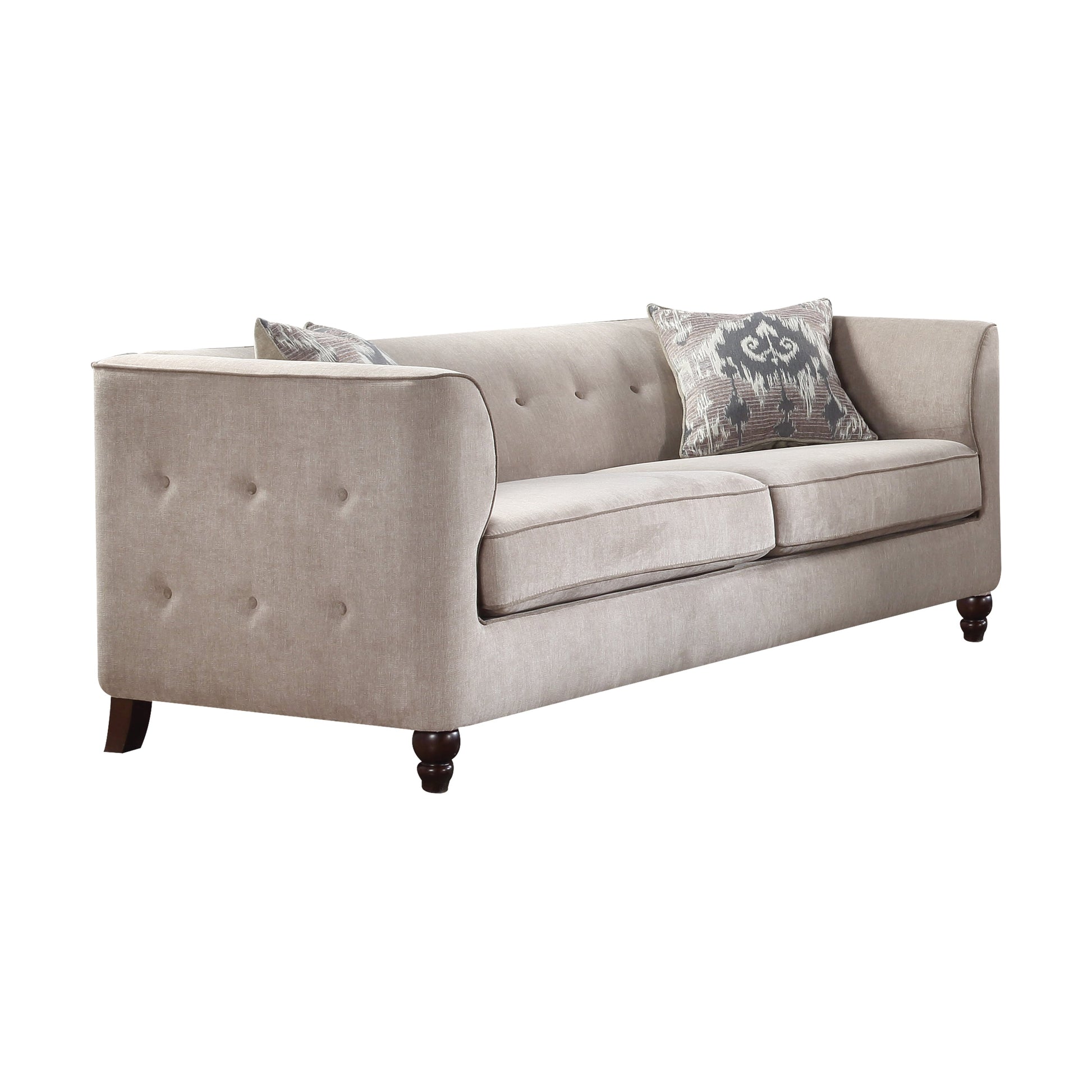 Tan velvet tufted couch shown with espresso wooden legs and two decorative pillows.