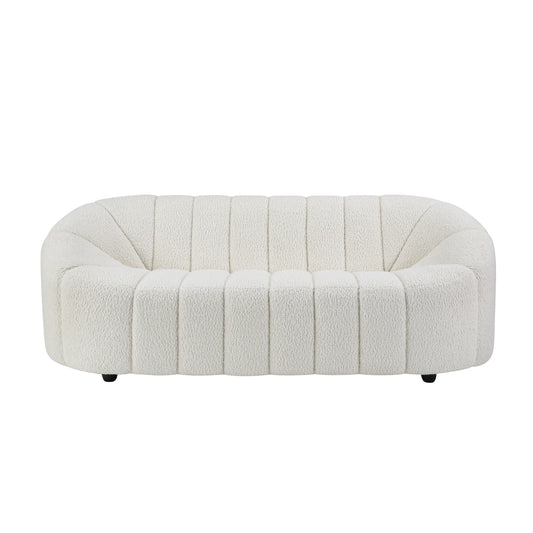 The Ellie Sofa is white with teddy sherpa upholstery. The Ellie sofa has modern curved armrests and vertical channel tufting detail.