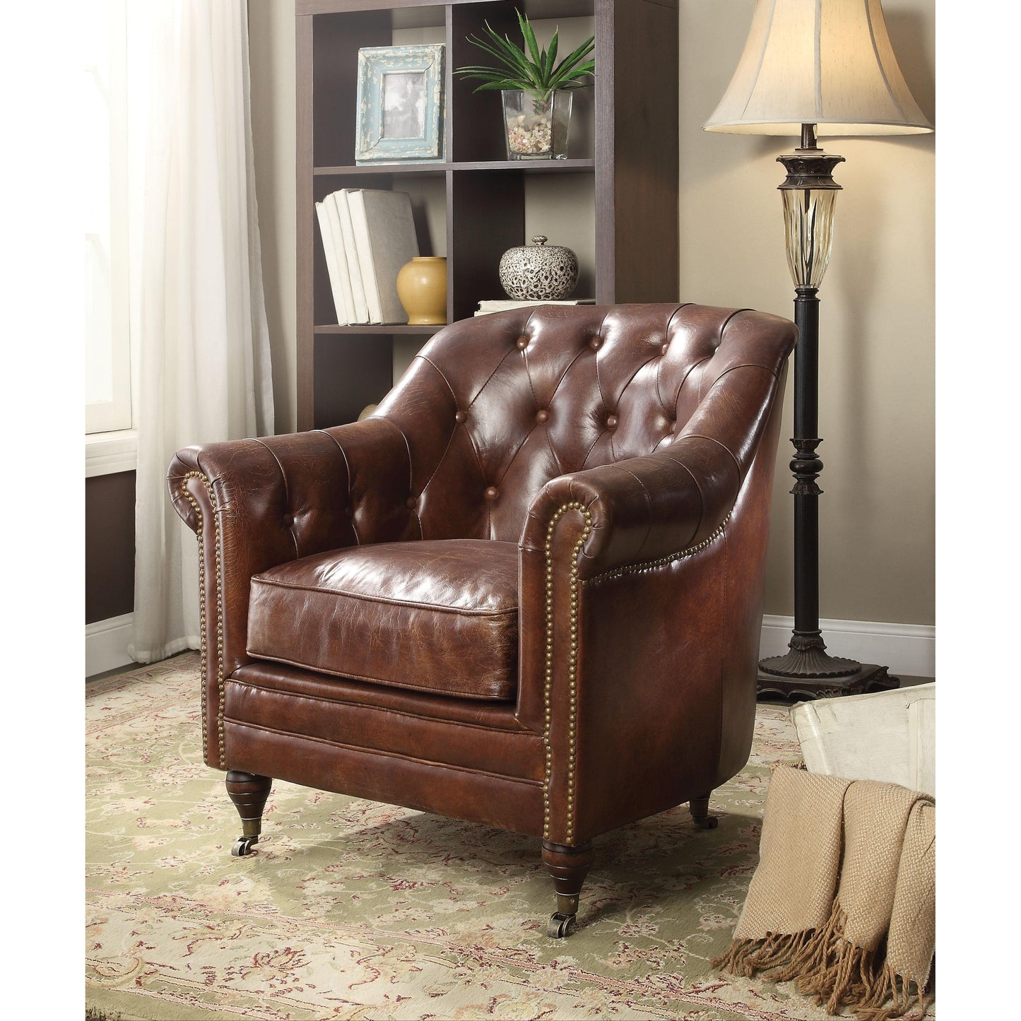 Dark brown leather accent chair with rounded arm rests and tufting details. The Legs of the chair are wooden with bronze metal casters.